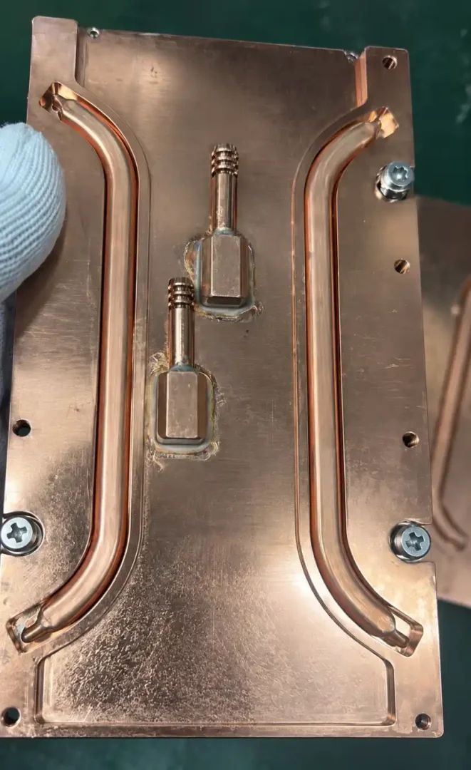 Copper cold plate with formed coolant tubes and two brazed connector blocks.
